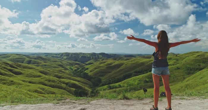 Traveler overlooking the rolling green hills of East Sumba, Indonesia.
