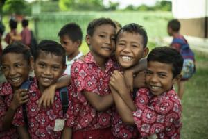 Smiling school children in Sumba wearing traditional red school uniforms.