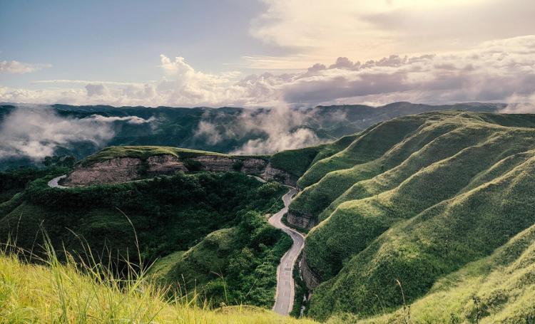 Scenic road winding through the rolling green hills of Sumba, Indonesia.