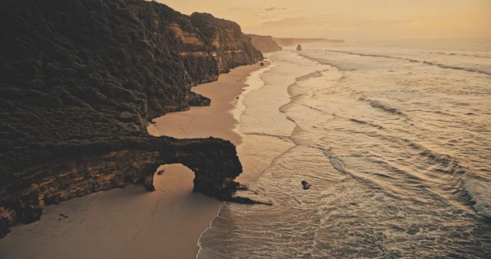 Aerial view of Pantai Bawana with natural rock arch and cliffs on the west coast of Sumba, Indonesia.