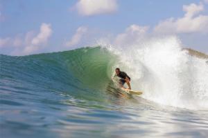 Surfer riding a breaking wave along the coast of Sumba, Indonesia.