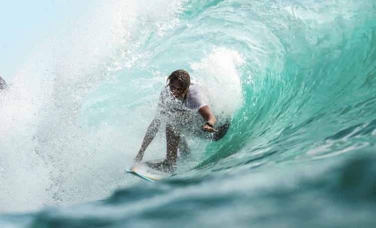 Surfer riding inside a turquoise barrel wave in Sumba, Indonesia.