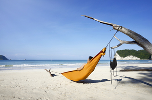 man relaxing in hammock at Tarimbang Beach Sumba with ocean and surf in background