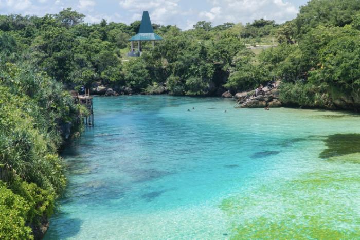 Crystal clear blue water of Weekuri Lagoon in Sumba with limestone cliffs and tropical greenery.